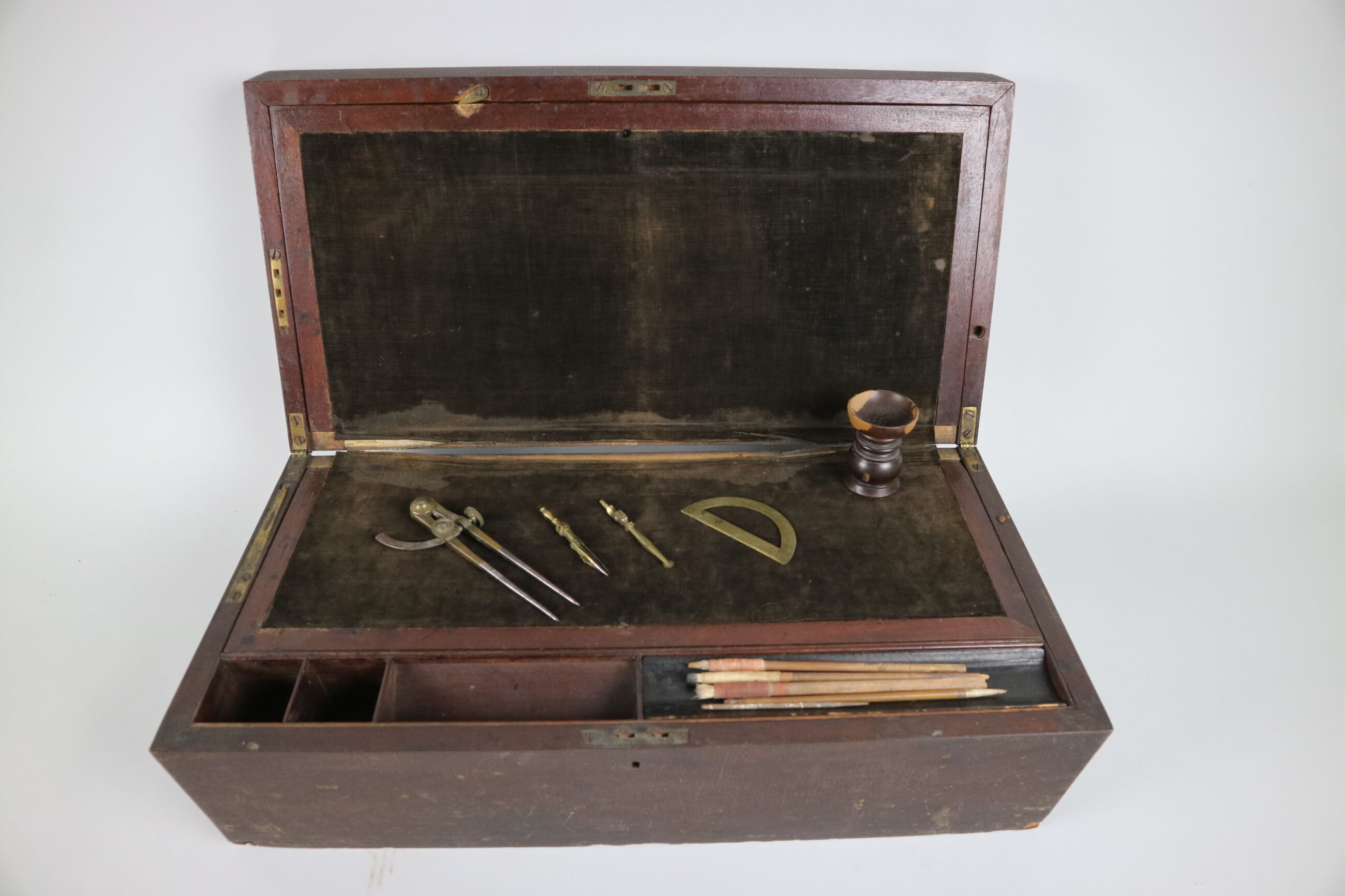 A portable writing desk with measuring tools and pencils inside. The desk resembles a wooden box and is made of reddish wood.