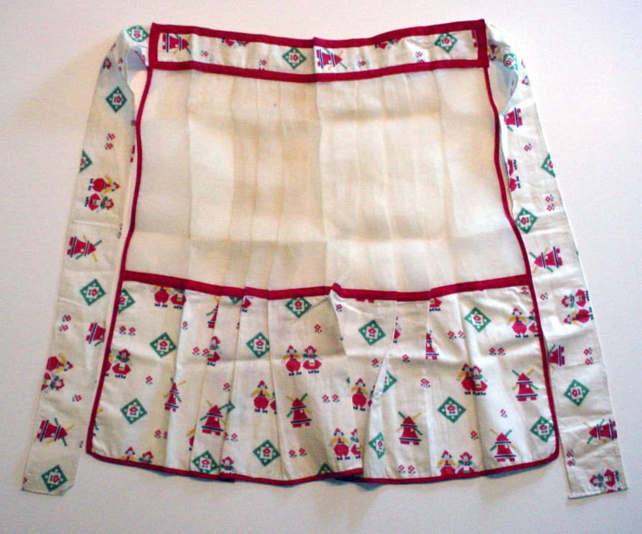White apron with red details and little elf-like figures.