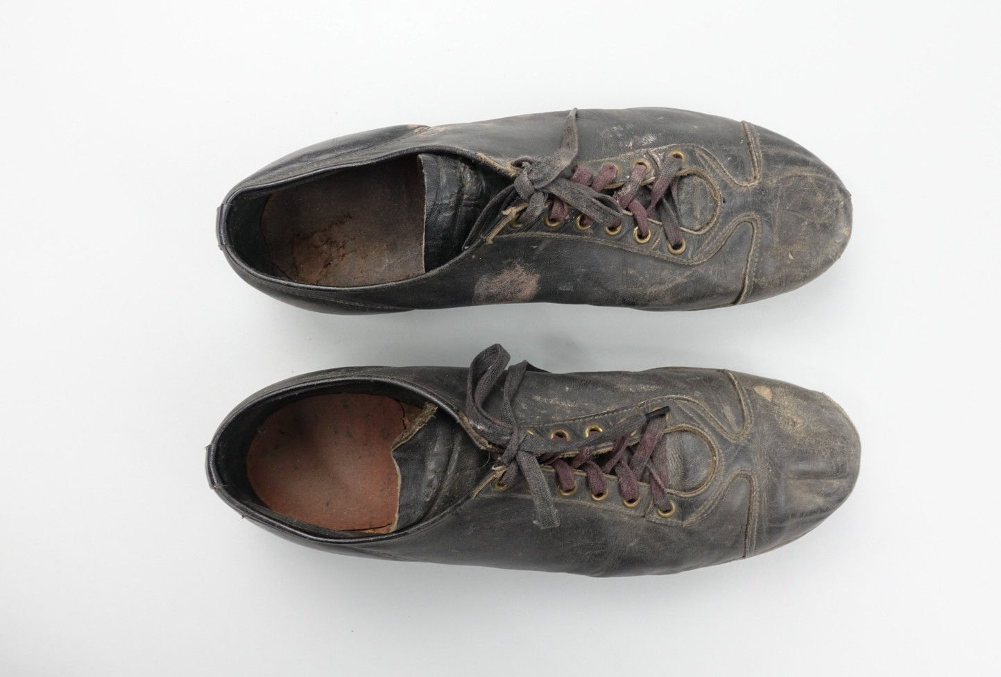 Photograph of a pair of old black leather lace-up sports shoes
