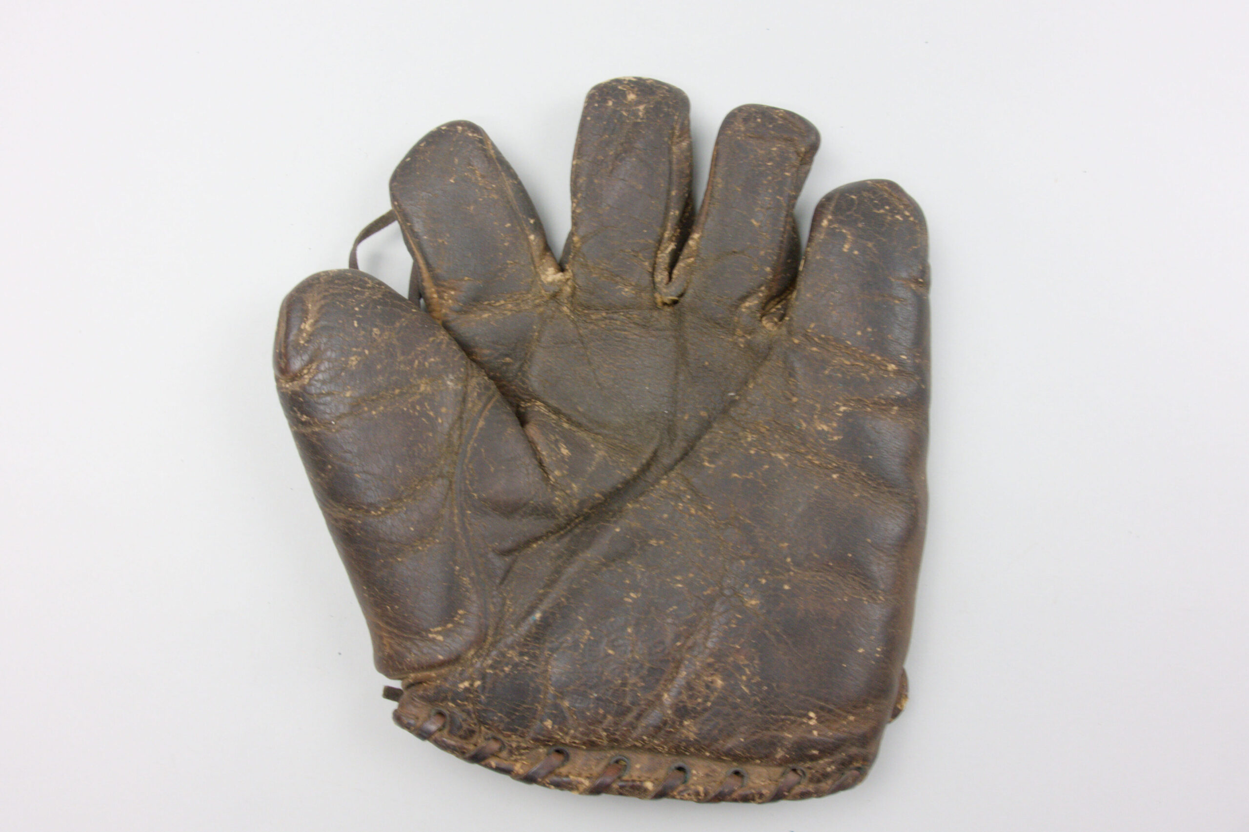 Old dark brown leather baseball glove, with separated fingers and a small piece of leather connecting the index finger and thumb.