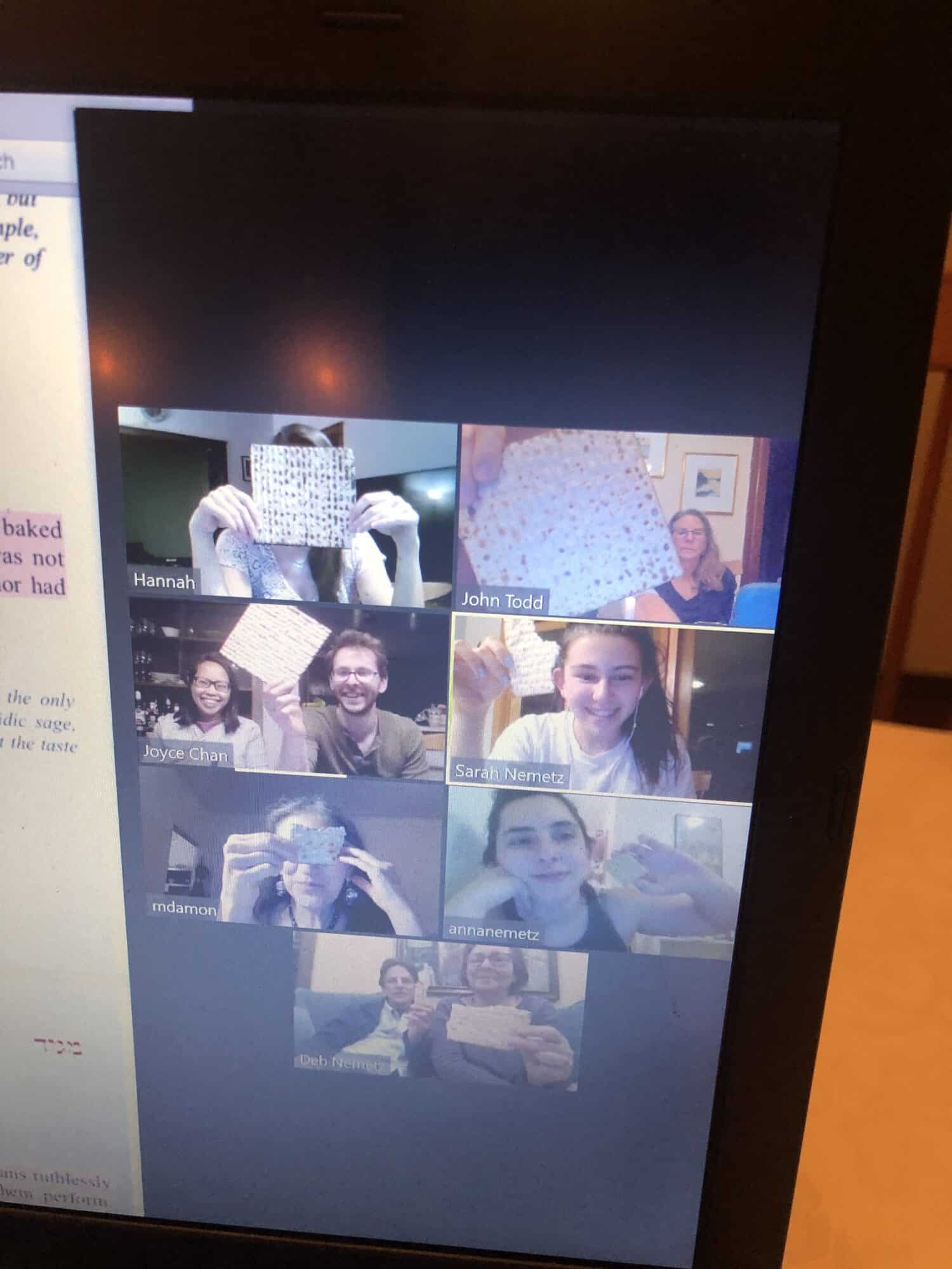 a photograph of a group call on computer, showing images of one or two people in seven squares, each holding up a piece of matzah bread