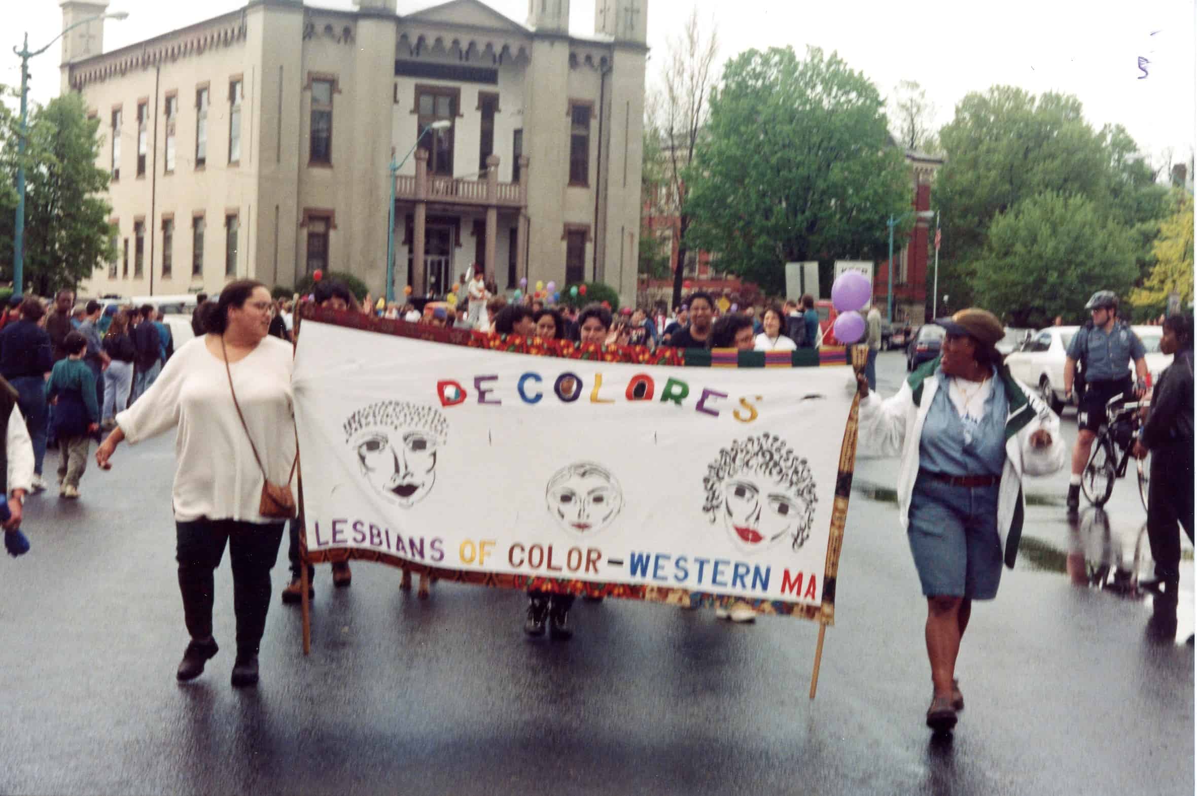women holding a banner while walking on Main Street, Northampton City Hall in background