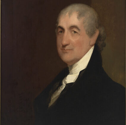 Portrait of a middle aged Caleb Strong. He has a gray mullet-style hairdo and a black and white suit.