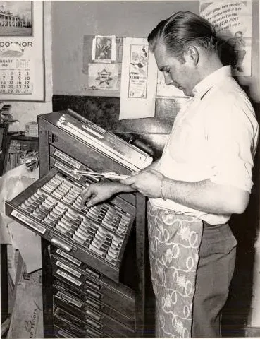 Black-and-white photograph of a middle-aged man working at the Daily Hampshire Gazette.
