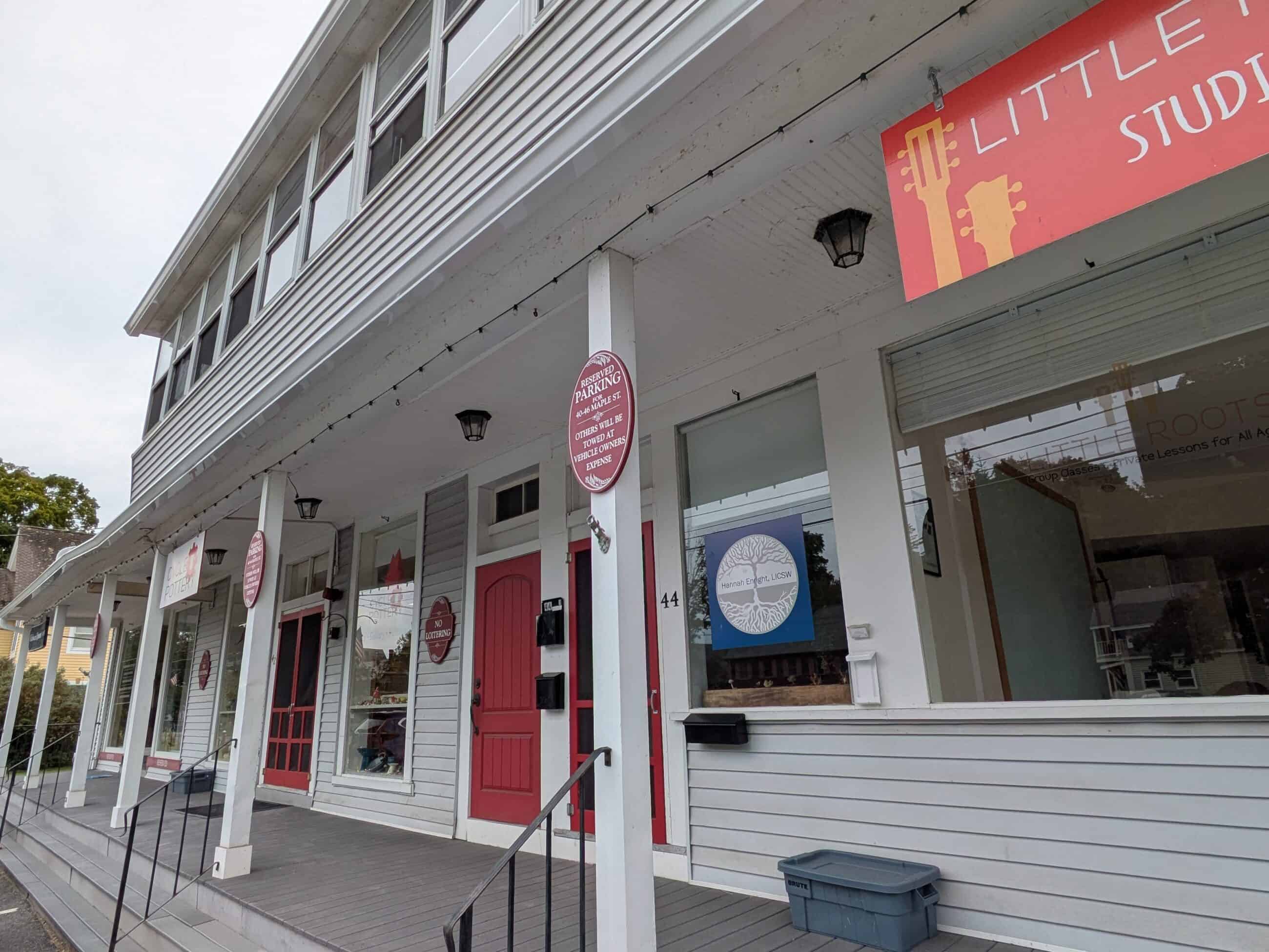 Photograph of old Cutler Block. The building is white with red details and has been modernized. Multiple storefronts in view but signs are not fully readable.