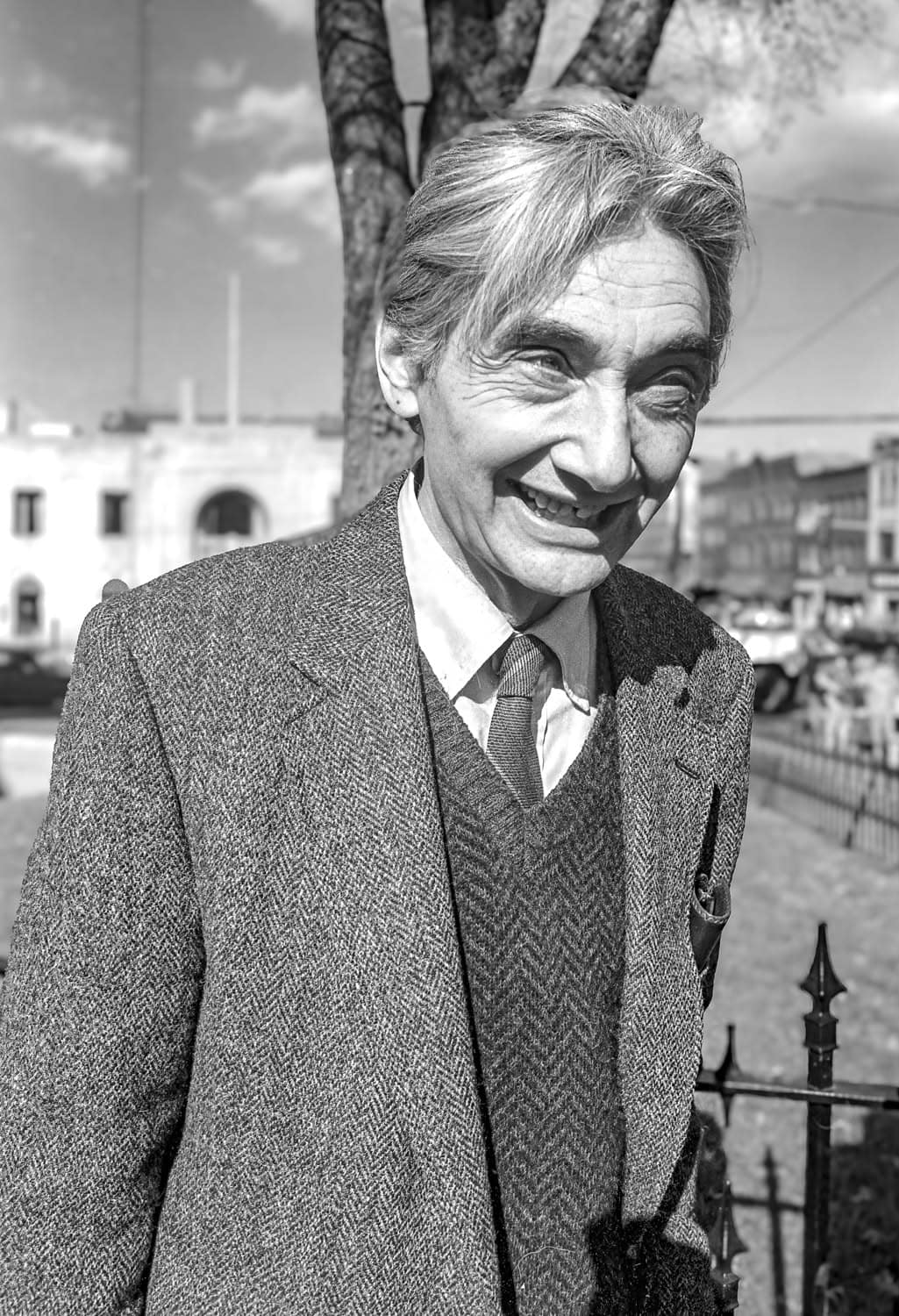 Photograph of a matured man at the courthouse on Main Street (Northampton). He looks past the camera off to the distance smiling and has a gray-and-white suit on. His hair is gray or white.