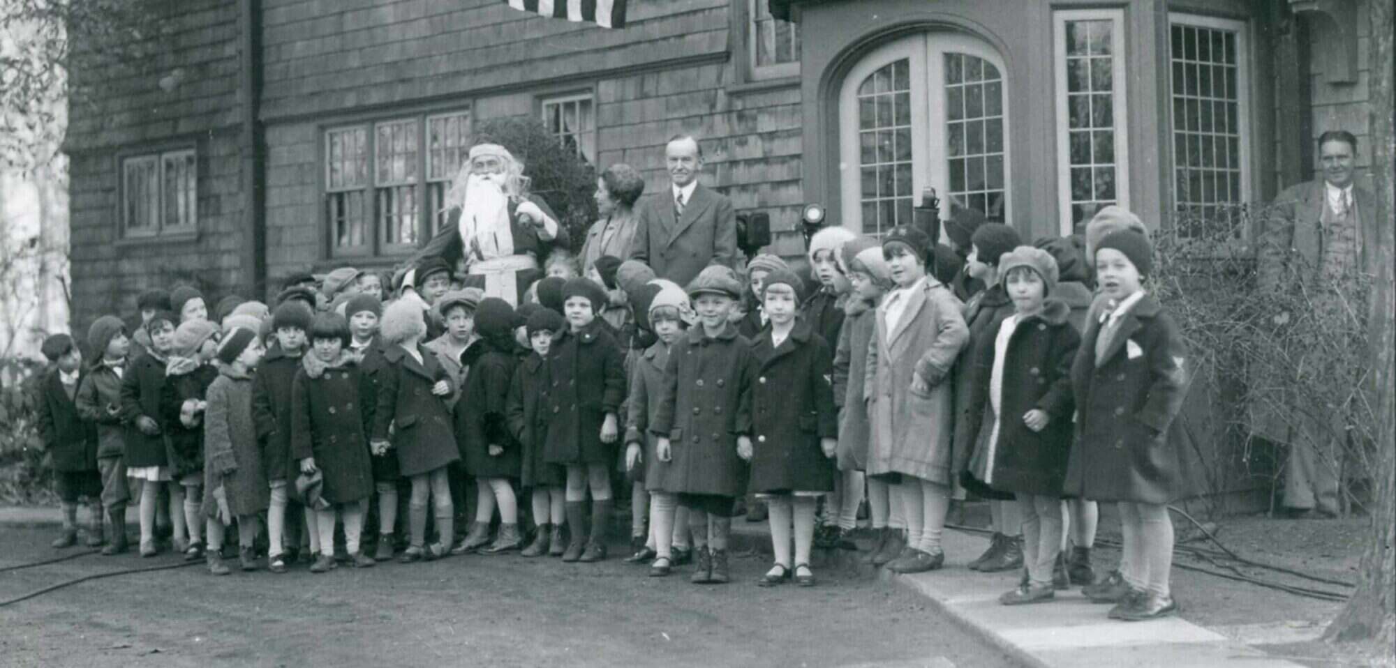 A group of young children, with Santa and Grace and Calvin Coolidge in front of the Coolidge family home, Beeches.