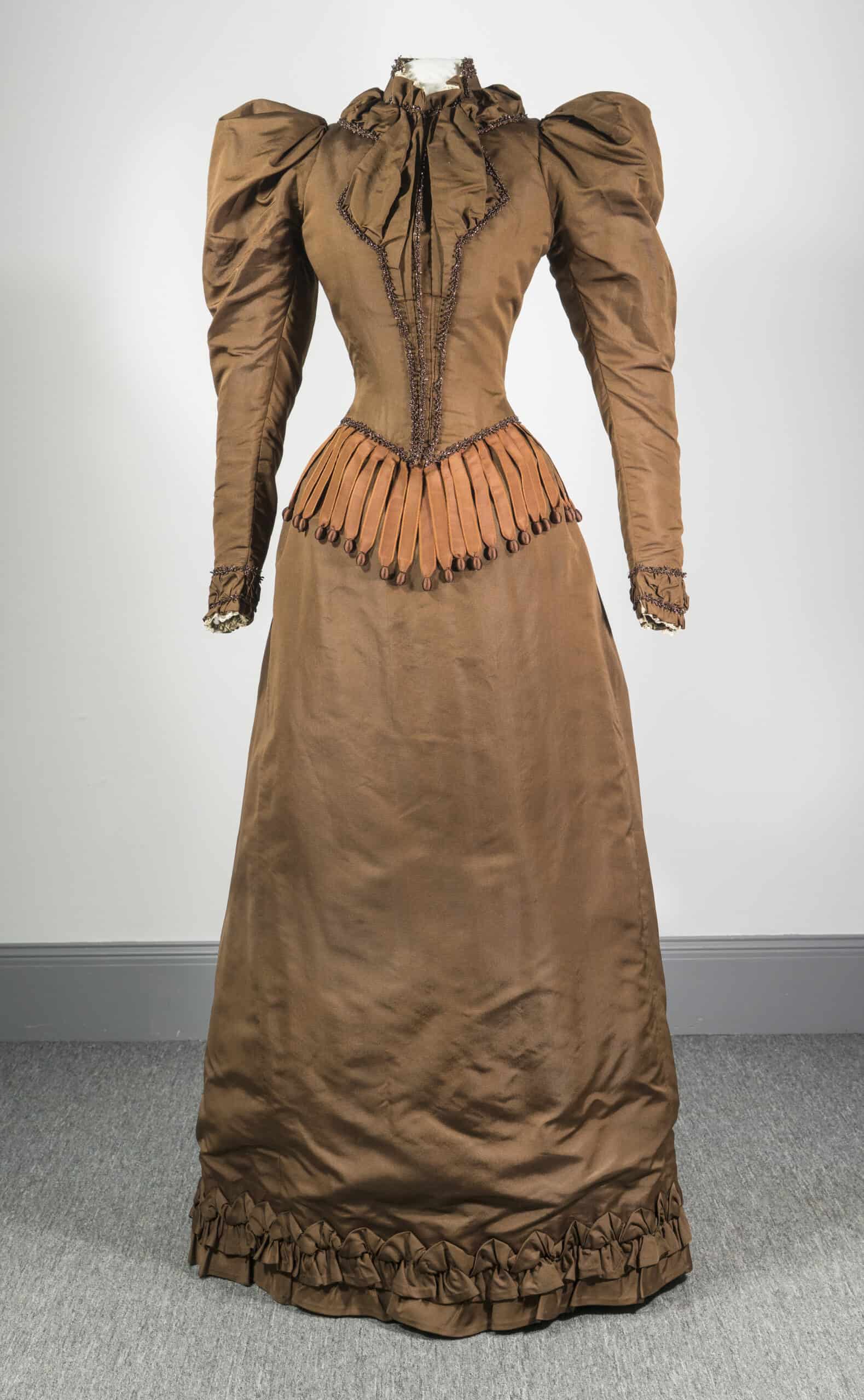 Front of orange-brown wedding dress with a small pointed waist and puffy shoulders.