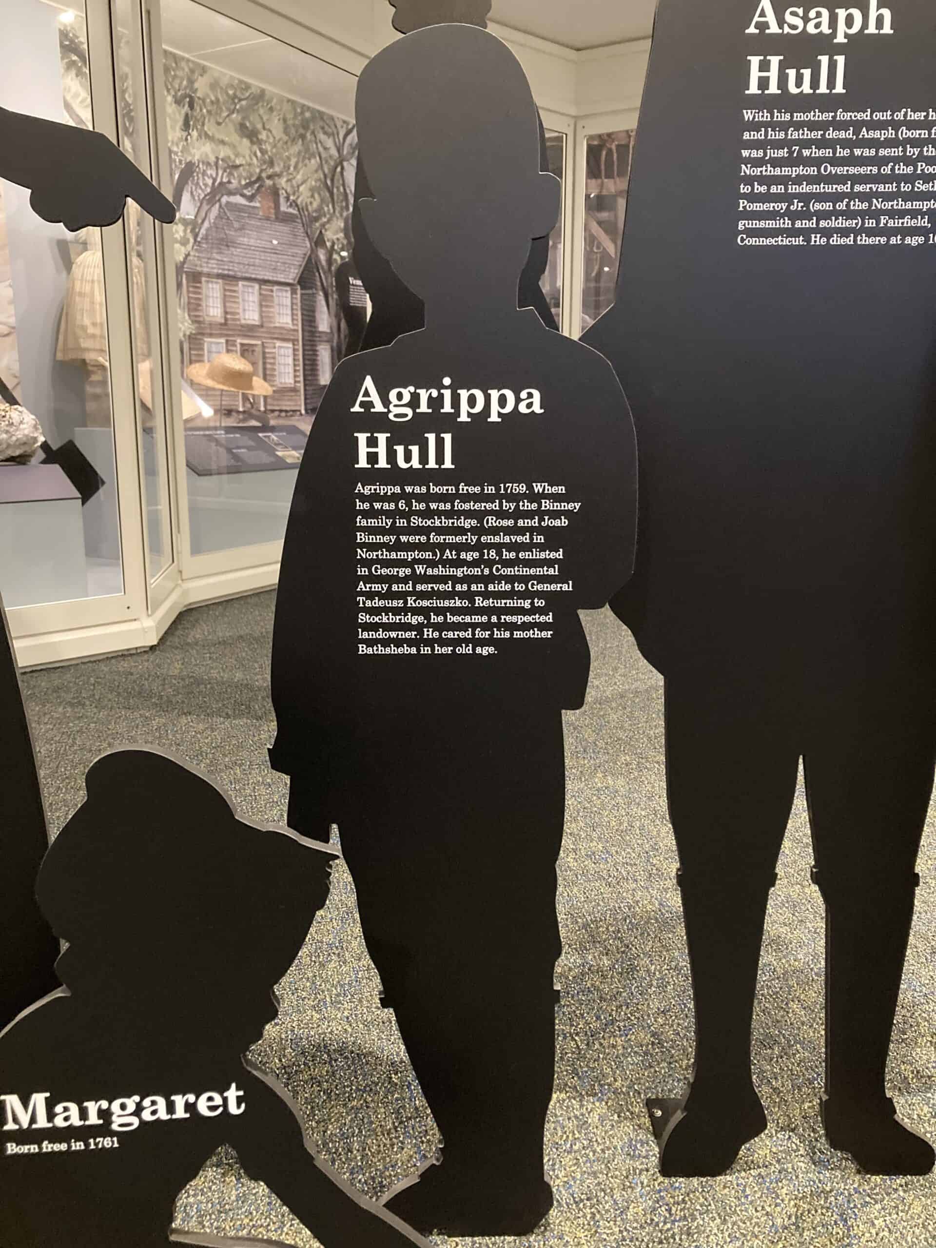 Photograph of life-size black silhouette of a young child in a museum gallery, with the text "Agrippa Hull" and additional writing on the figure