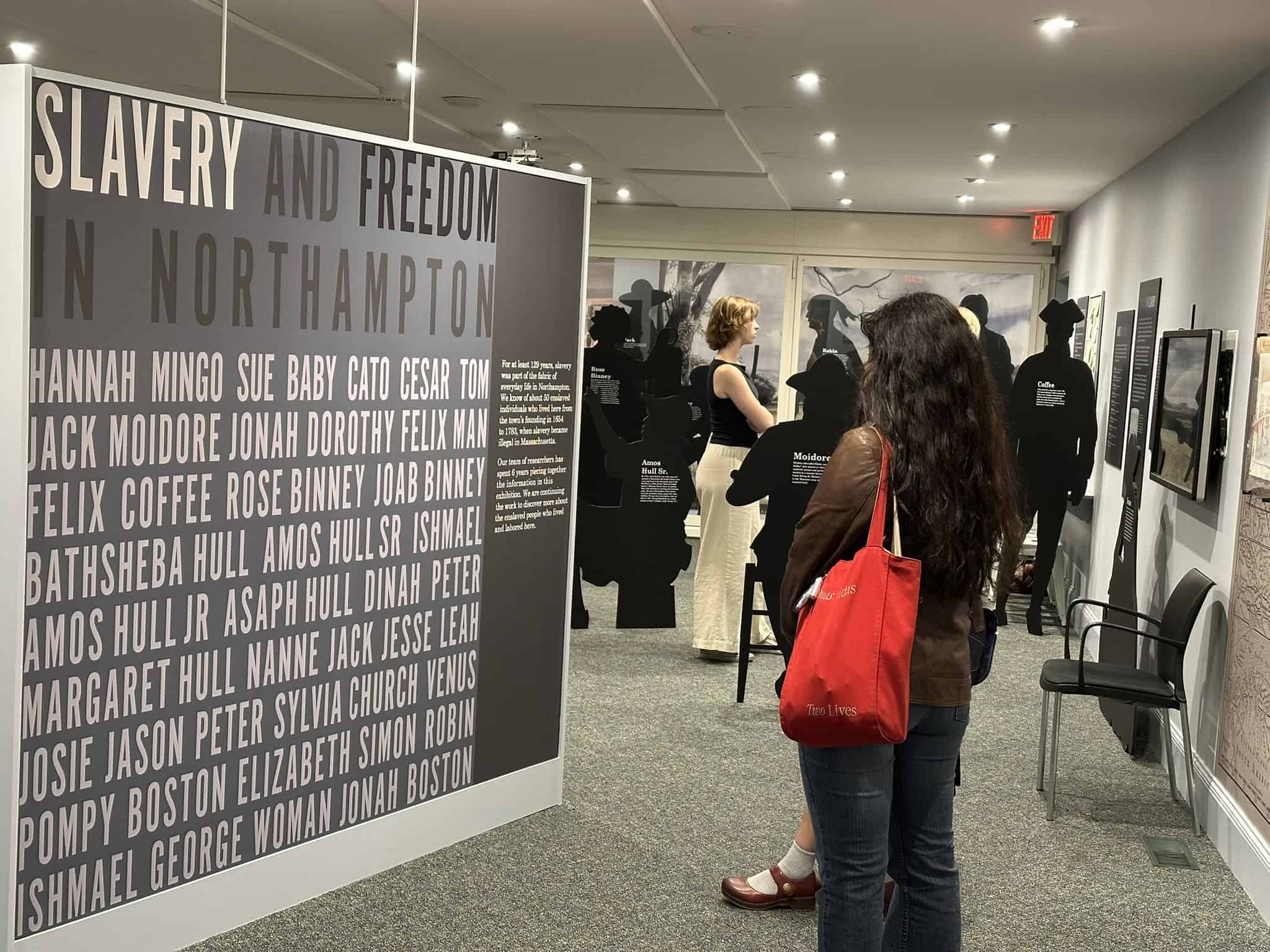 Photograph of a young woman or girl reading a poster in the Slavery in Northampton exhibit at Historic Northampton.