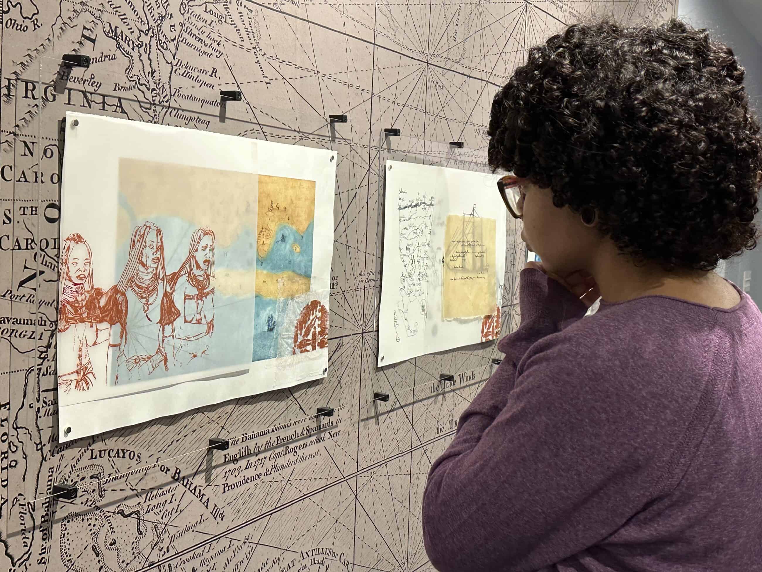 A young woman or girl looking at artwork posted on a wall with a map design in the Slavery in Northampton exhibit at Historic Northampton.
