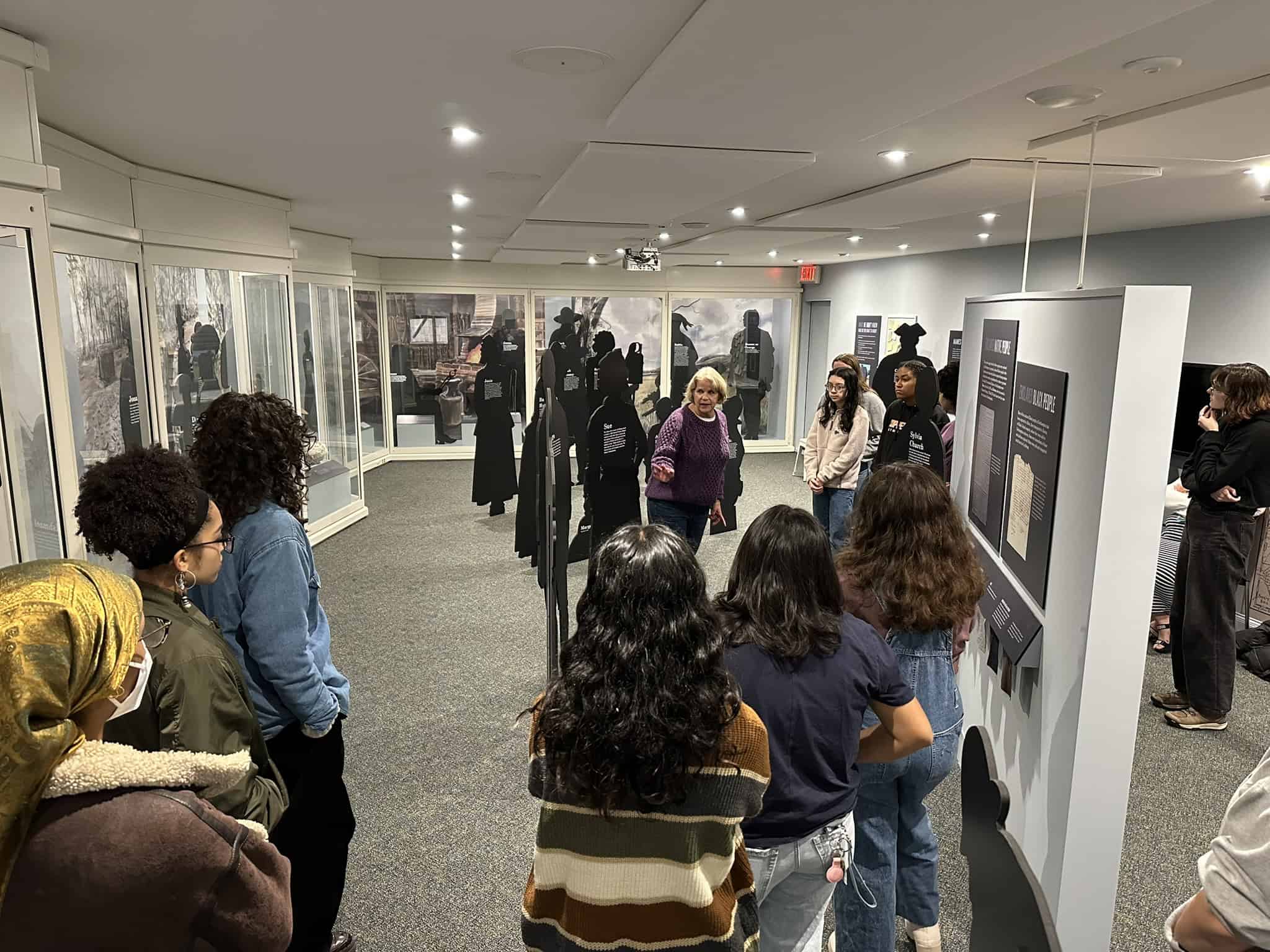 Teenaged students listening to Betty Sharpe discuss the Slavery in Northampton exhibit.