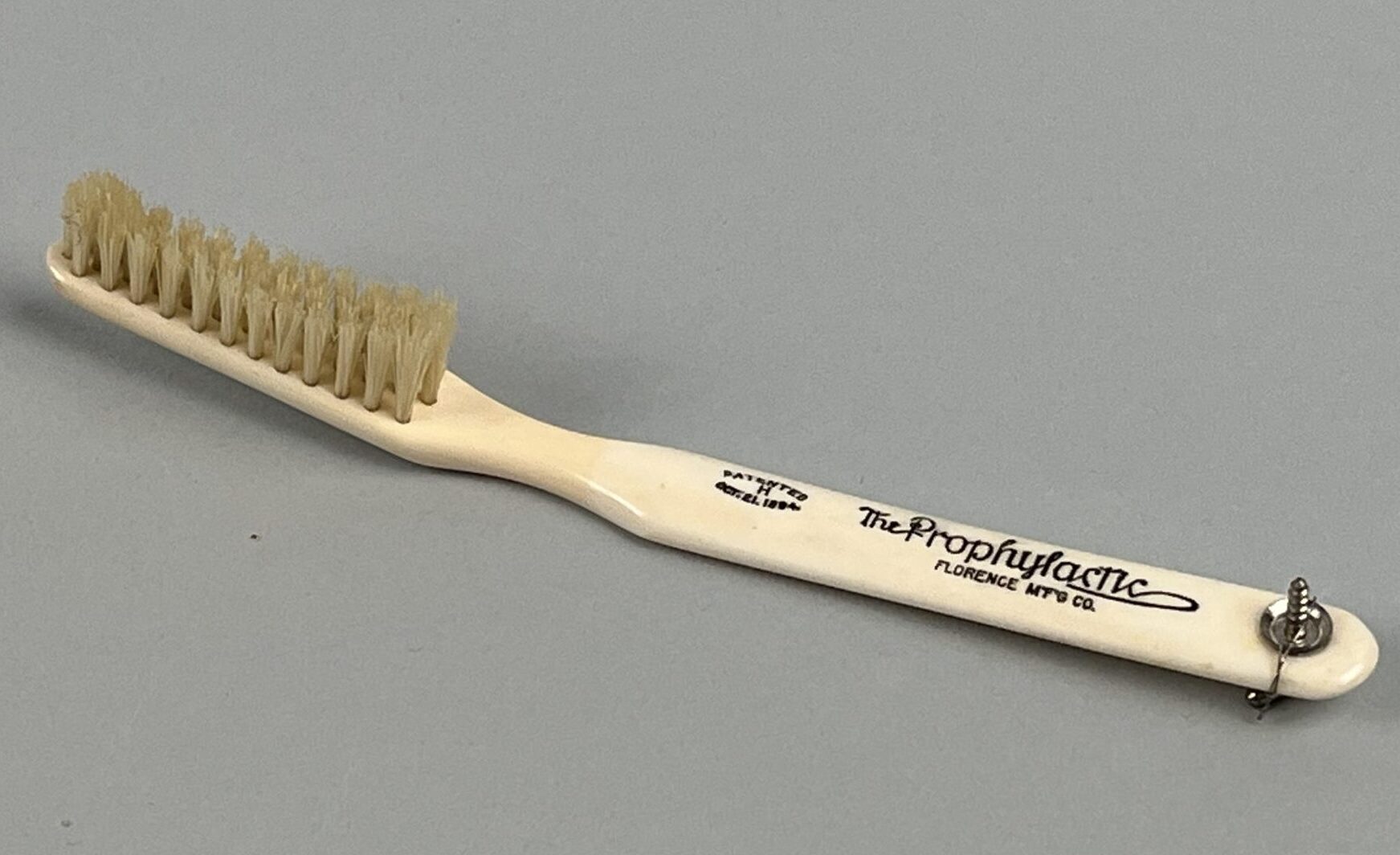 A toothbrush with a pale ivory handle which reads The Prophylactic Florence Mfg Co