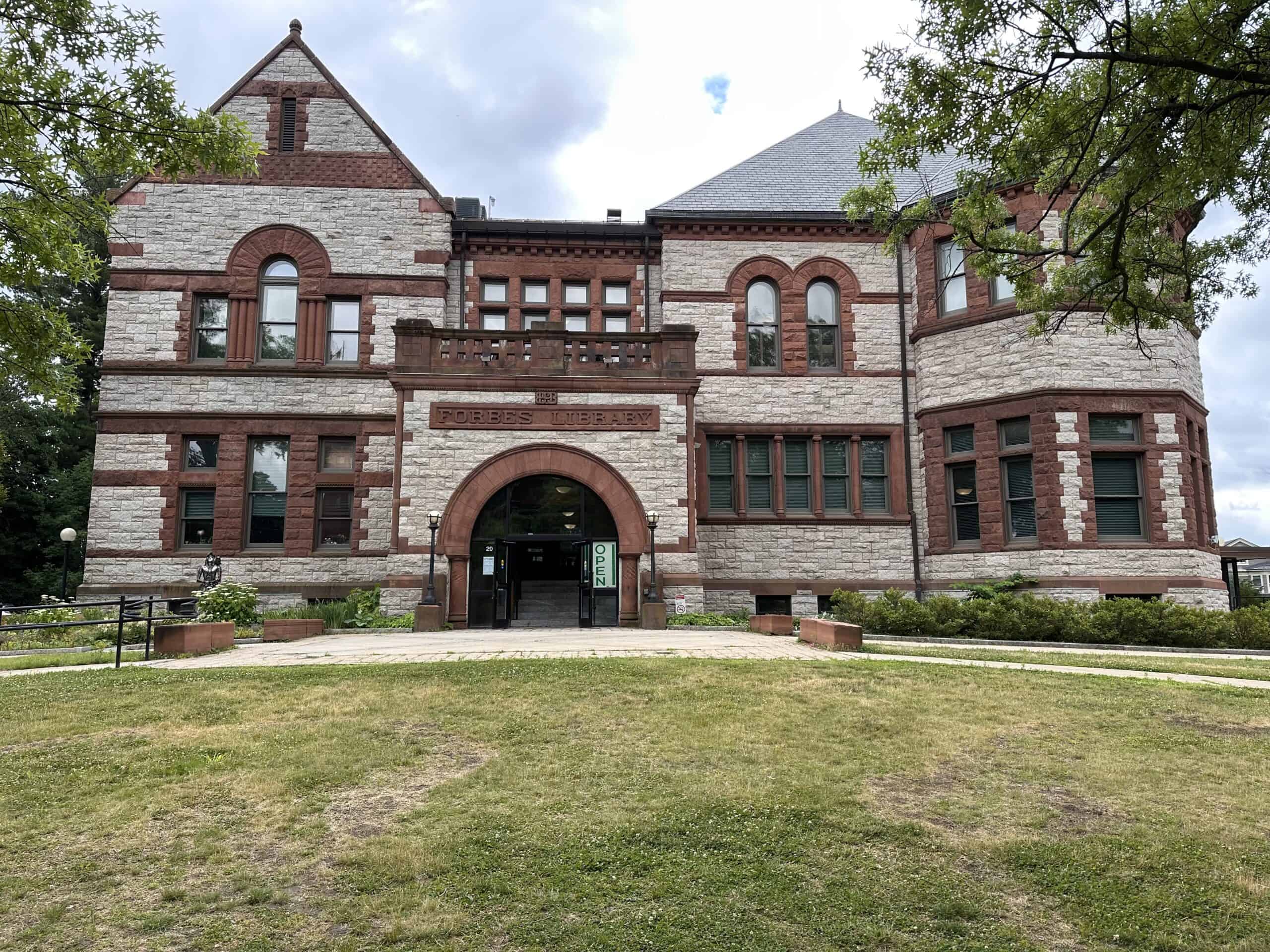 Color photo of a stone building with arched doorway and lawn in foreground.