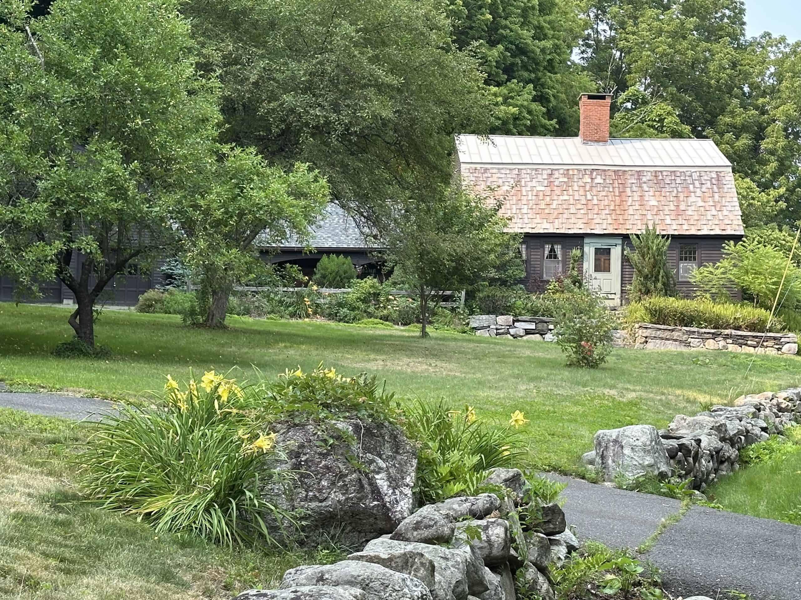 The same location, Robert's Meadow, in a more recent photo, with a low stone wall, trees and flowers.