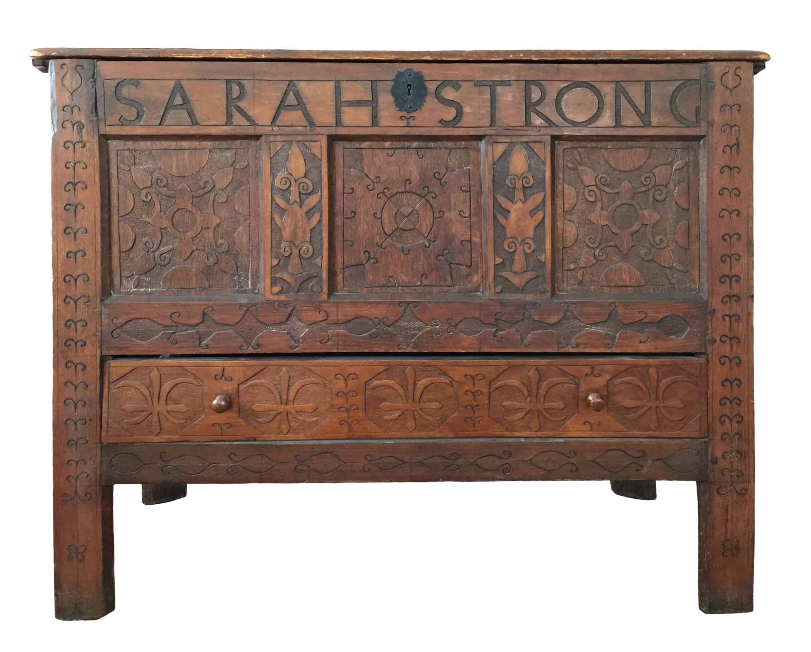 Photograph of the Sarah Strong chest. The chest is wooden with designs engraved into it. Toward the top of the chest reads in bold letters: "SARAH STRONG".
