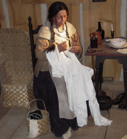 This life-size diorama portrays a Pequot home in the mid-1800s, typifying the ways in which Native people combined Indigenous and European material goods and lifeways. Note the distinctive Native elements in this woman’s garb – braided hair, beaded necklace, and deerskin moccasins. Also note the variety of ash-splint baskets used for storage. Diorama at the Mashantucket Pequot Museum. Photograph by Margaret Bruchac.
