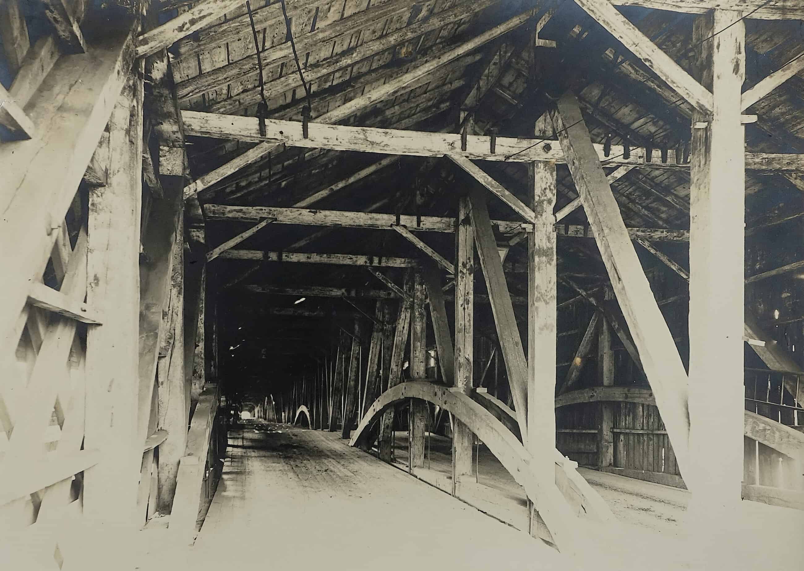 Black-and-white photograph of the interior of the bridge across Connecticut River. The bridge is wooden and has a slanted roof.