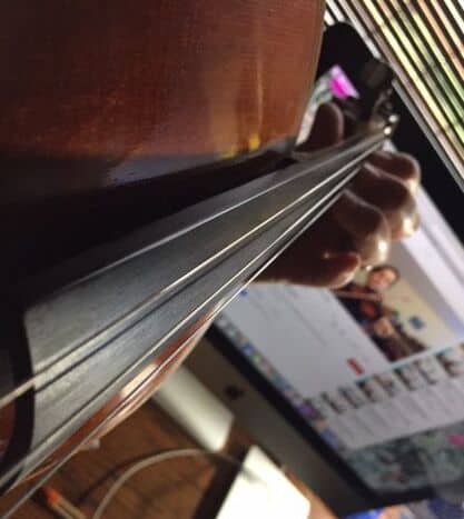 close-up photo of fingers pressing on the strings of an instrument