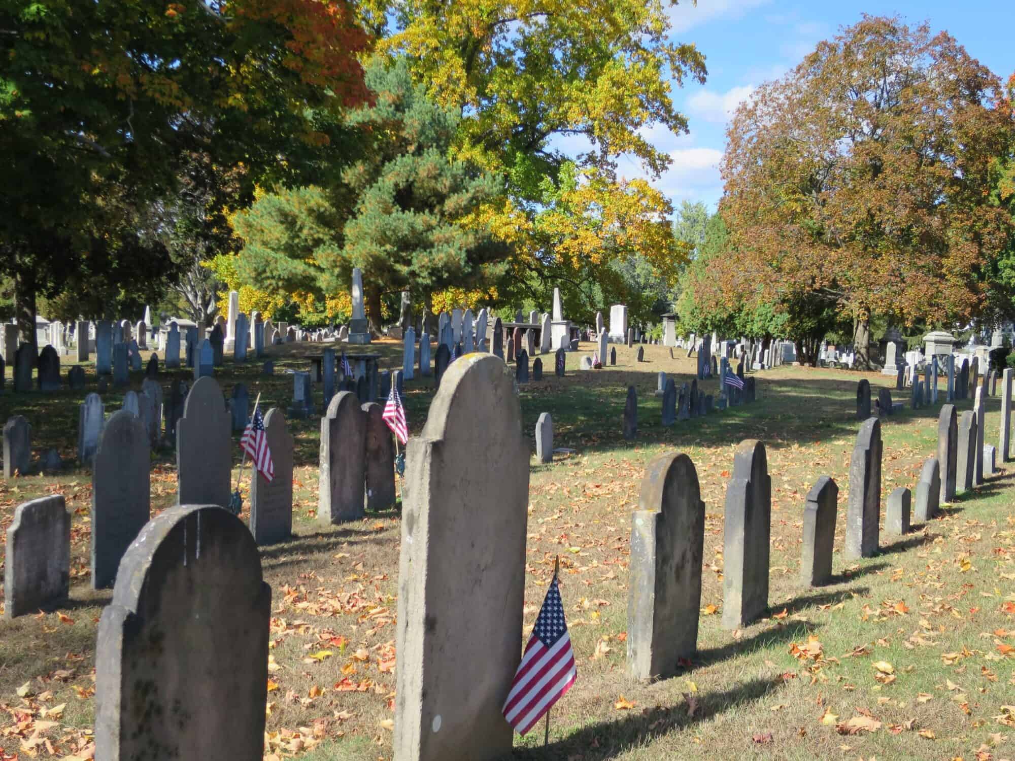 A view of thin gravestones in low light on a fall sunny day.