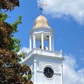 Photograph of a church steeple with clock and bell
