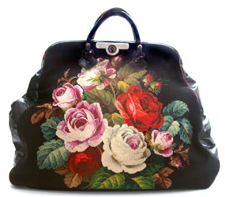 Image of a floral carpet bag. The flowers are pink, white, and red, with brown and green leaves. The bag closes in a coin-person type lock.
