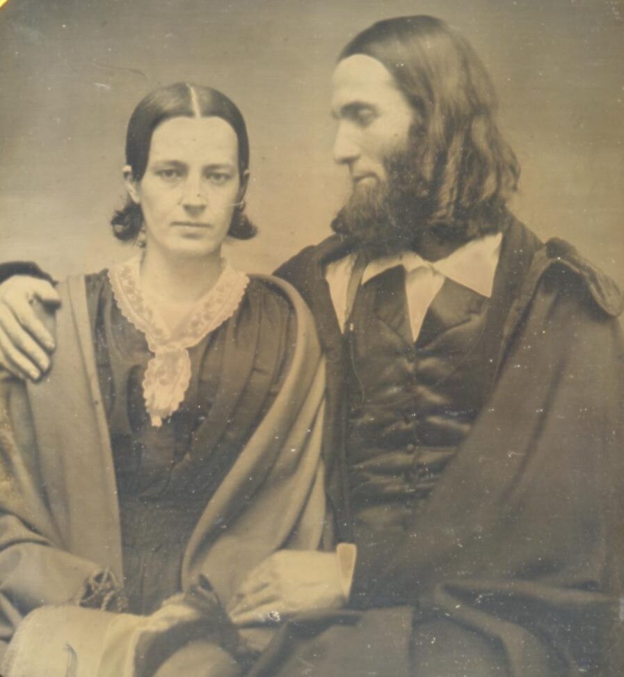 Half-plate daguerreotype portrait photograph of a woman, Gertrude Kimber Burleigh, seated next to her husband, Charles Burleigh, Sr. with his arm around her shoulder.