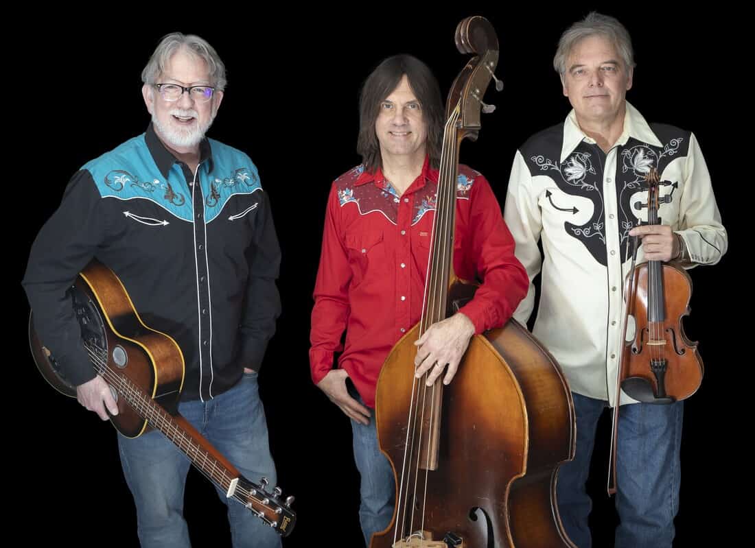 Color photo of three musicians, one holding a guitar, one with a Bass, and one with a fiddle.