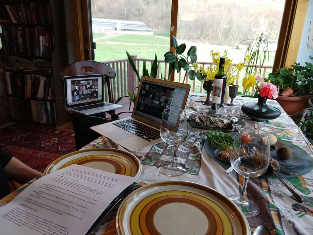 Photo of a table set with dishes and flowers and two open laptops