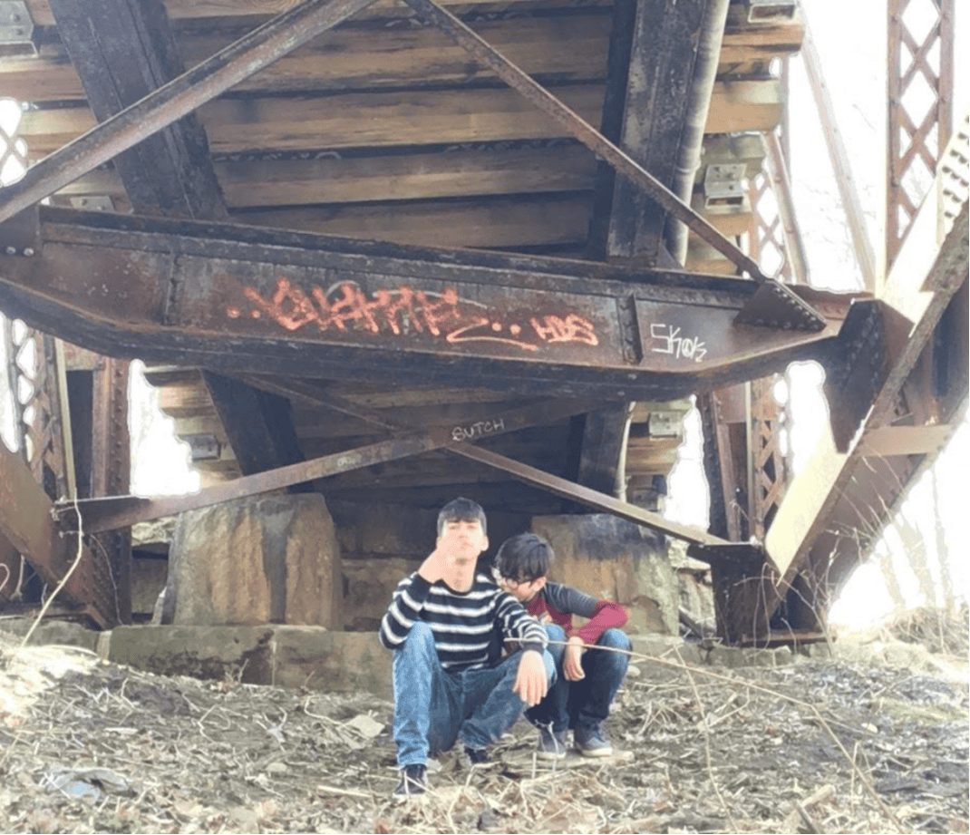photo of two boys sitting under a bridge