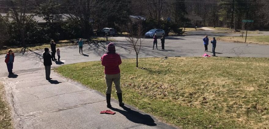 photo of people standing at a distance outside on street and sidewalk