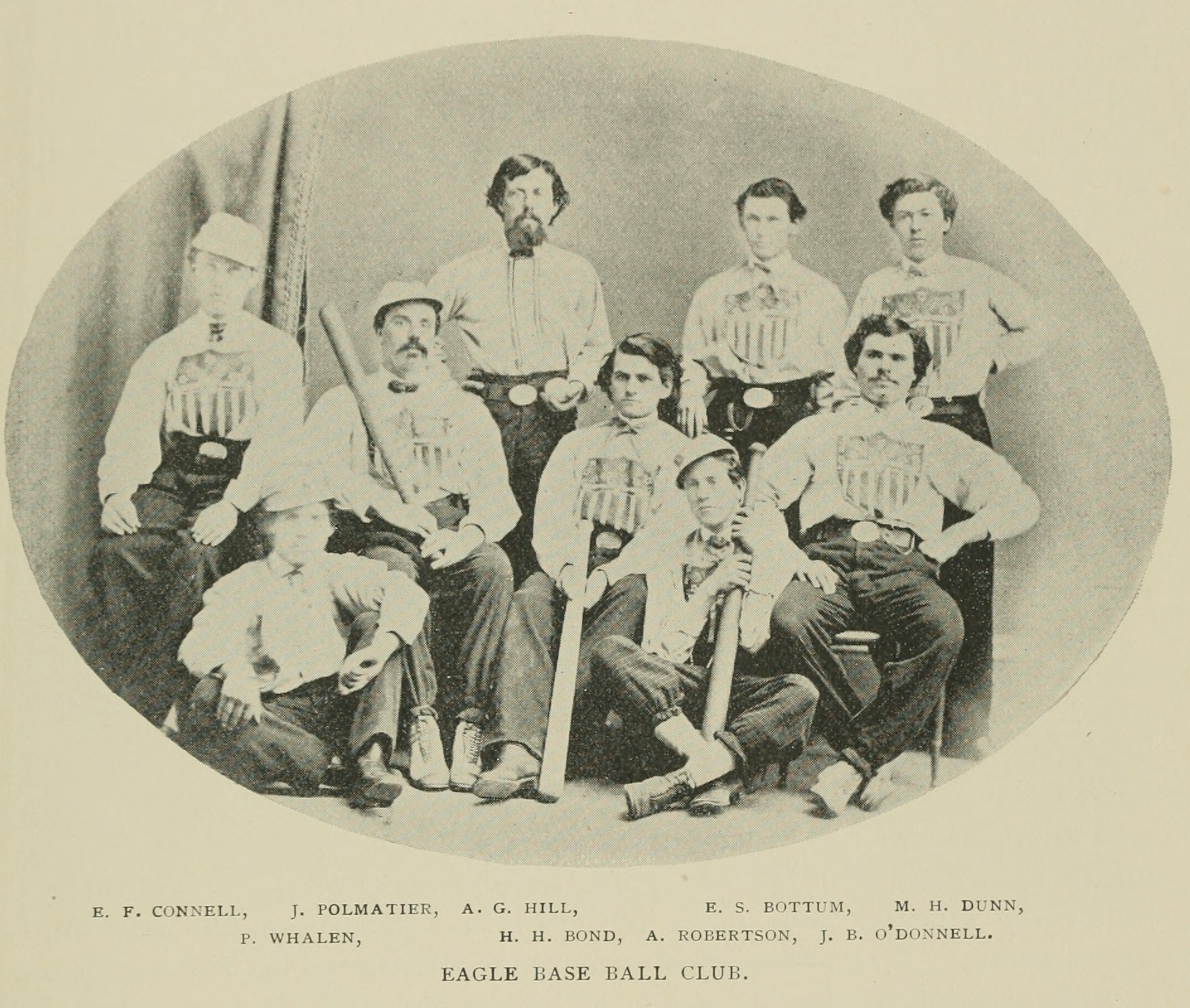 Oval-shaped black-and-white 19th-century photograph of nine adult male baseball players. Some are standing, some are seated in chairs, and two are seated on the floor. Most are wearing white long-sleeve uniform shirts with a crest-shaped logo. Three are holding wooden baseball bats. One is holding a baseball. Below the photograph is a list of player names, reading, "E. F. Connell, J. Polmatier, A. G. Hill, E. S. Bottum, M. H. Dunn, P. Whalten, H. H. Bond, A. Robertson, J. B. O'Donnell. Eagle Base Ball Club."