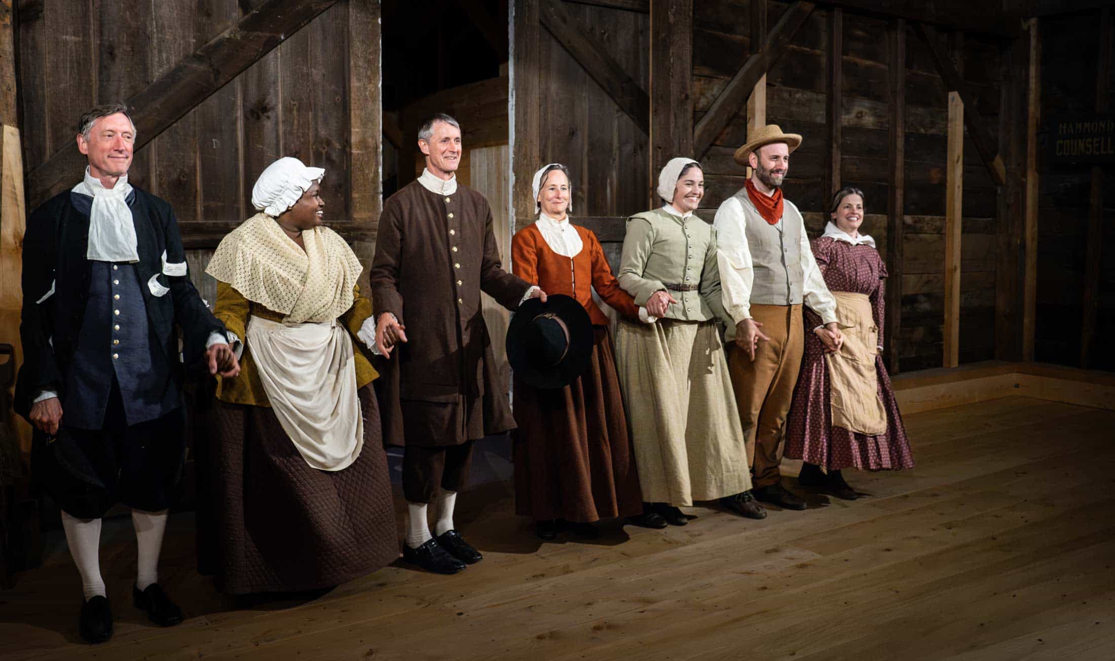 A row of actors stand and take a bow, in costumes from the 1700s.