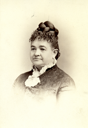 Black-and-white portrait of a woman with an elaborate updo and a black and white dress. The portrait is cut off at the chest.