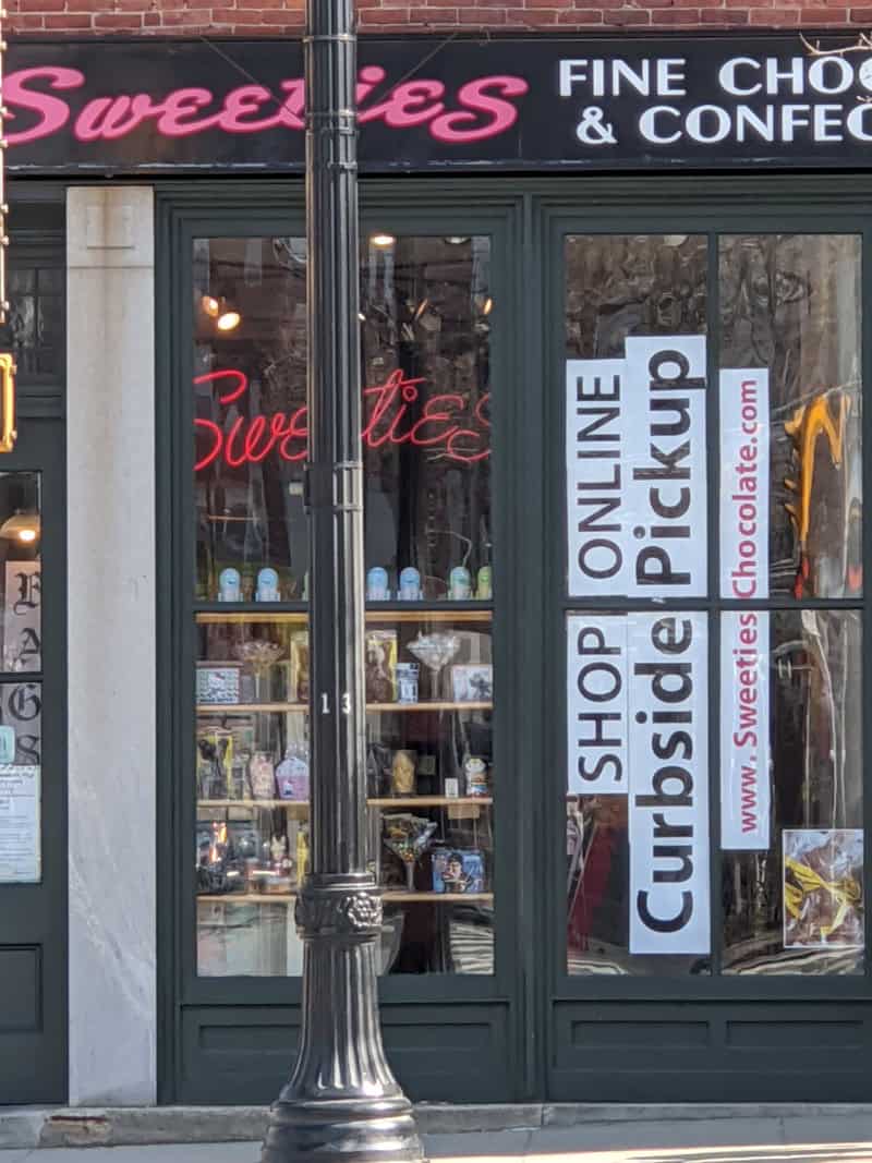 Photo of Sweeties store window with sign Shop Online - Curbside Pickup