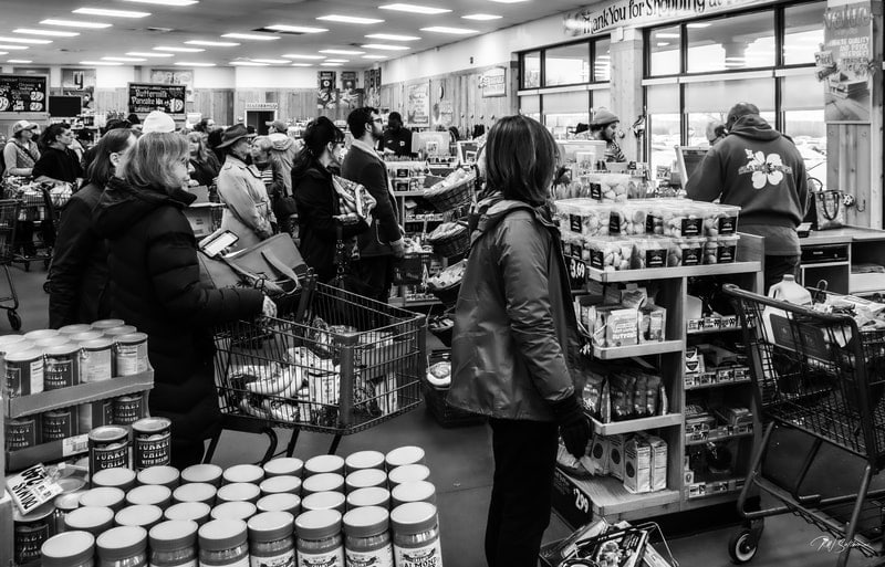 Photo of people in long checkout lines at grocery store