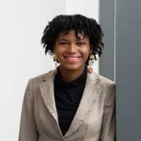 photograph of a young black woman, smiling and leaning on a door frame