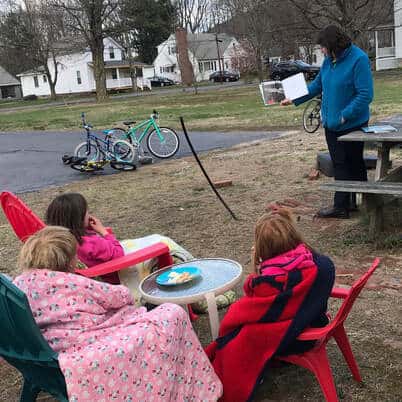 photo of a woman reading to a group of young children outside