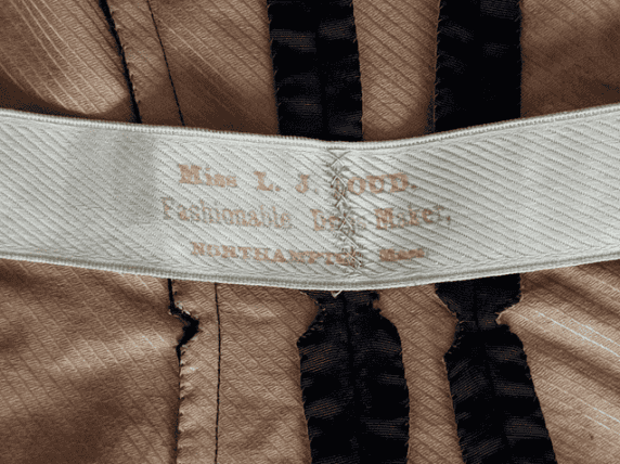 Photograph of a tag on the inside of a piece of clothing. The tag is white with yellow print.