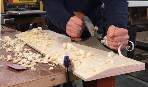 close-up of person using a wood plane