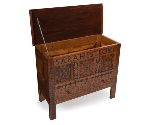 Photograph of the Sarah Strong chest replica with the lid propped open. The chest is wooden with designs engraved into it. Toward the top of the chest reads in bold letters: "SARAH STRONG".
