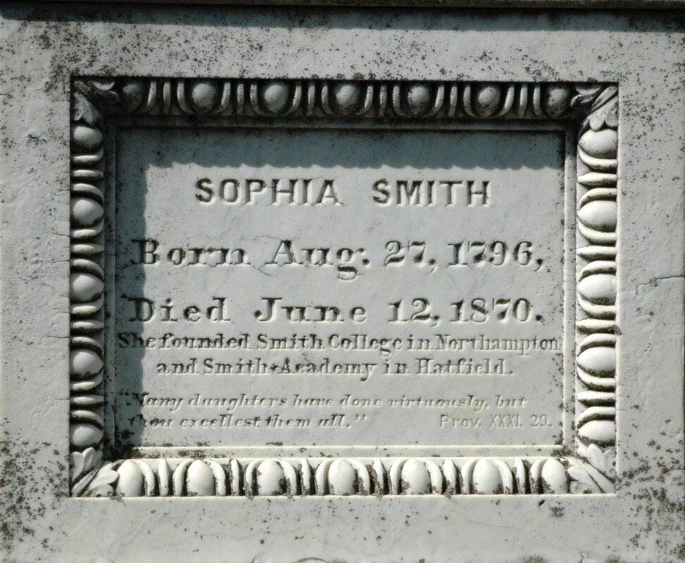 A close-up photograph of a weathered, rectangular marble headstone plaque framed by an ornate, carved egg-and-dart border pattern. The inscription is carved into the stone in capital and serif lettering, reading:"SOPHIA SMITH / Born Aug. 27, 1796, / Died June 12, 1870. / She founded Smith College in Northampton / and Smith Academy in Hatfield. / Many daughters have done virtuously, butthou excellest them all.” Prov. XXXI. 29."