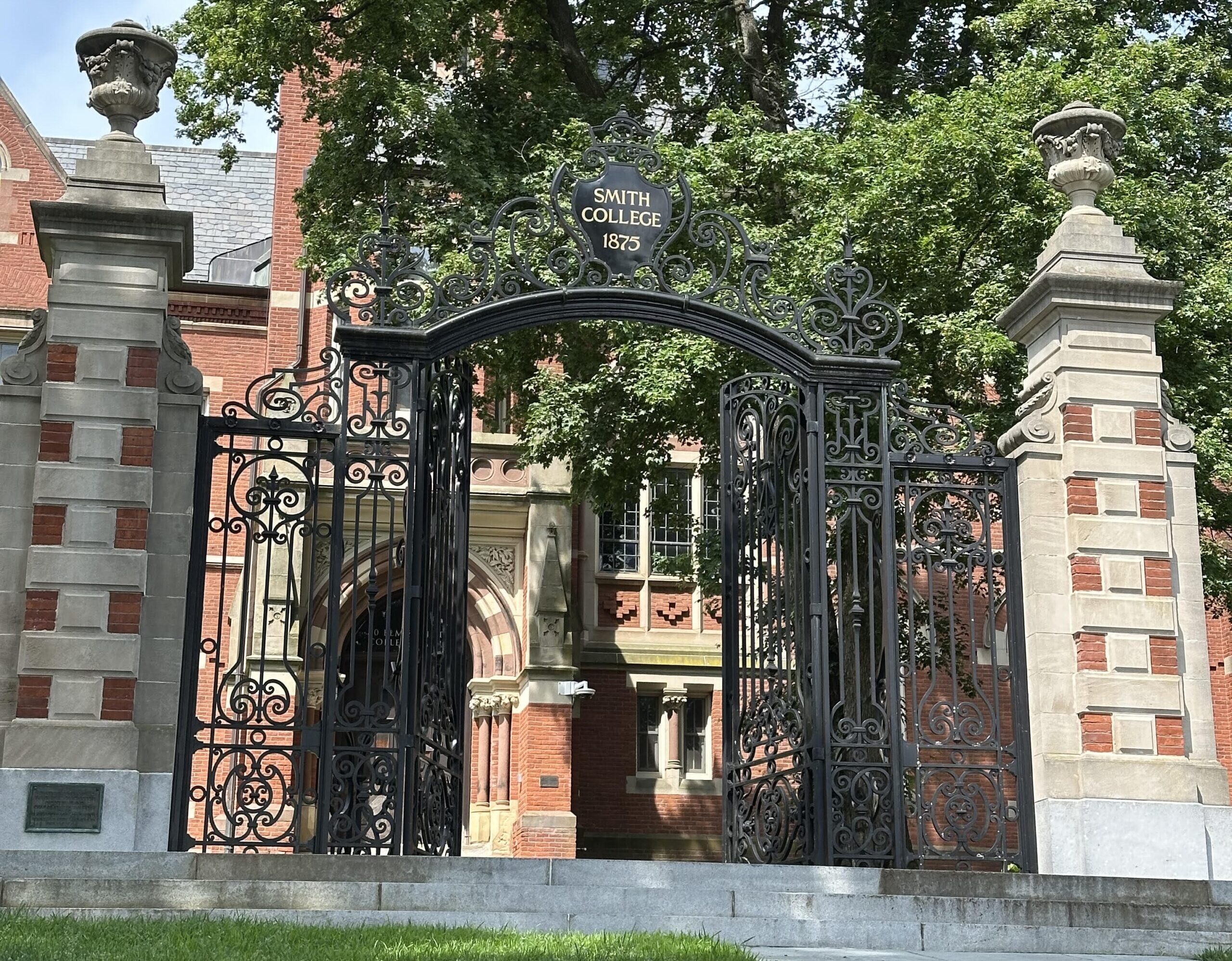 The entrance gate (a large black iron gate with brick and stone columns on either side) to Smith College, 1875.