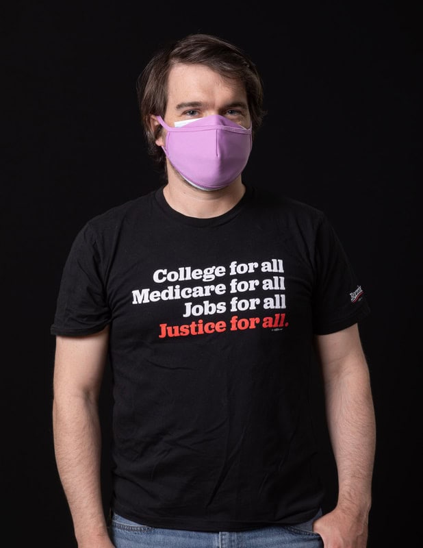 photo of person wearing face mask and t-shirt reading 'College for all, Medicare for all, Jobs for all, Justice for all'
