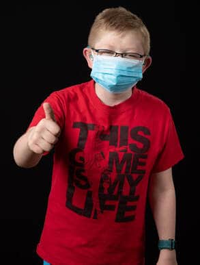 photo of young person wearing face mask and ared t-shirt reading 'This Game is My Life' with thumbs up