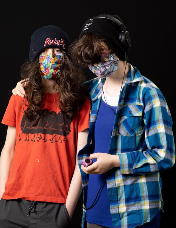 photo of two young people wearing face masks and hats