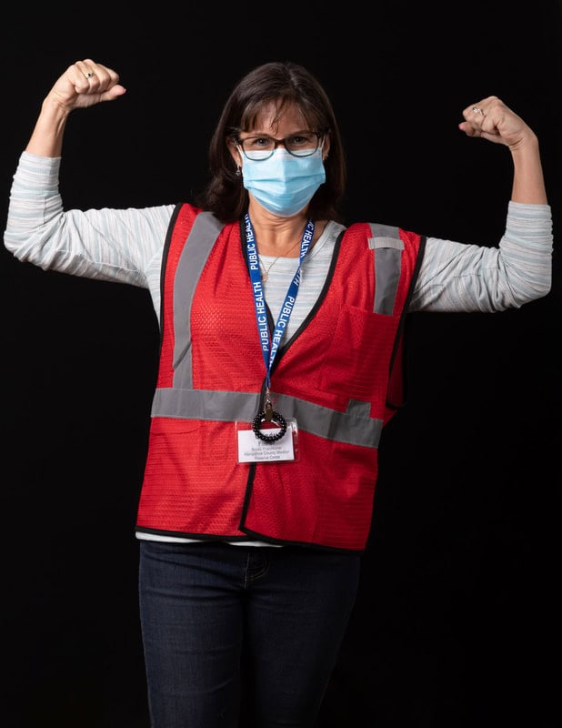 photo of person wearing face mask and red vest with two arms held up in fists