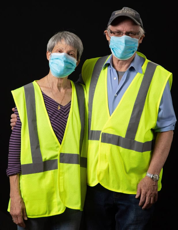 photo of two people wearing face masks and yellow vests