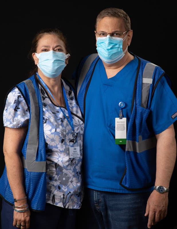 photo of two people wearing face masks and blue vests and scrubs