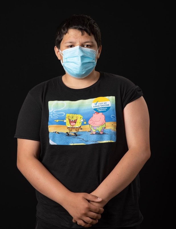 photo of young person wearing face mask and a Sponge Bob t-shirt and 'I got my Covid Vaccine sticker'
